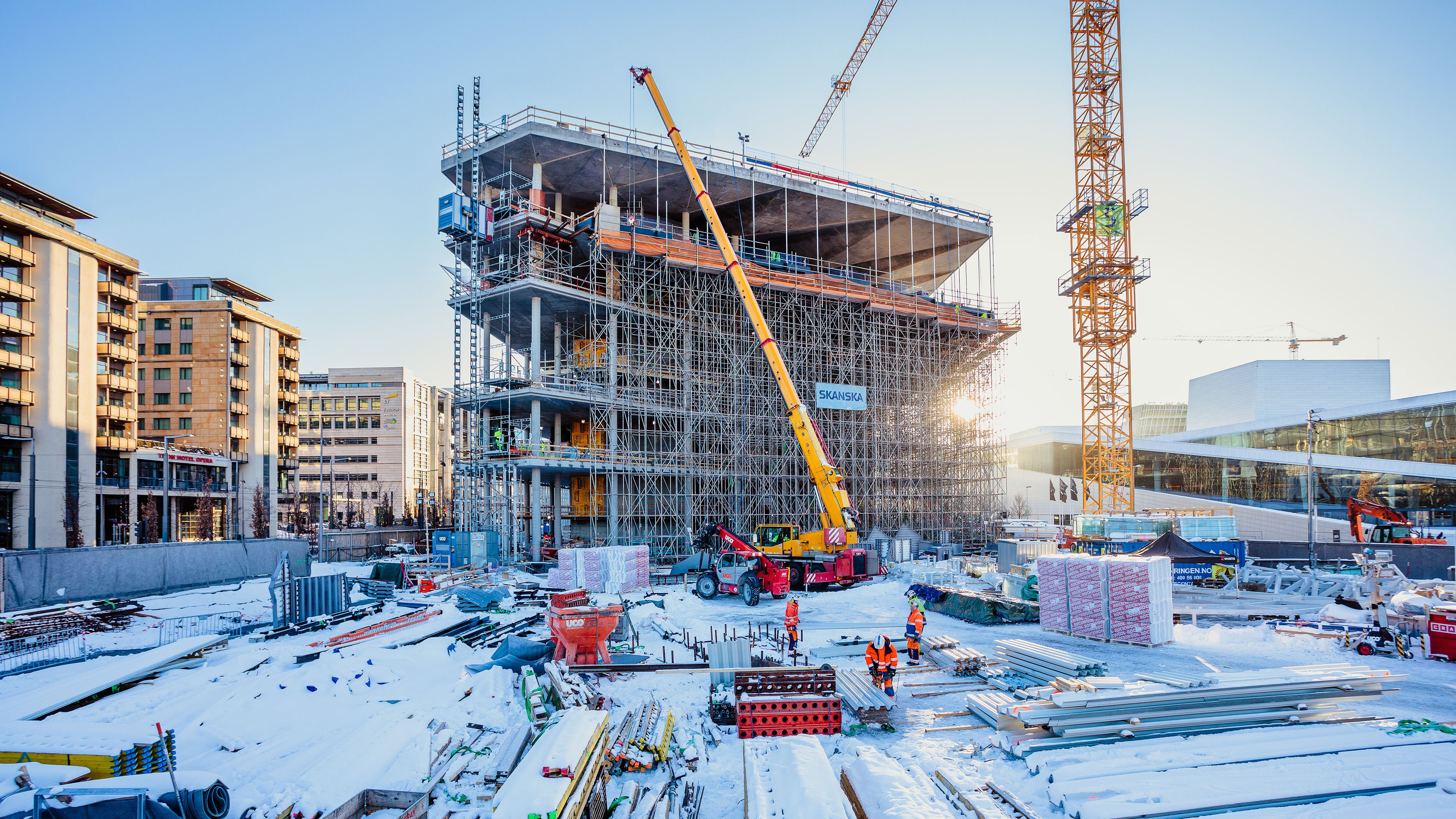 Byggeplass med et høyt bygg, stillas og kraner midt i Oslo ved Operaen